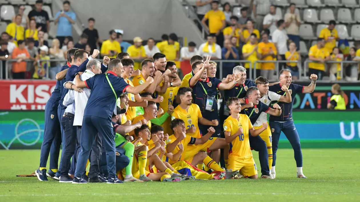 Tinerii tricolori ai naționalei U19 se bucură pe gazon alături de staff-ul tehnic, după ce au învins Danemarcu cu 3-0 pe stadionul Arcul de Triumf din București