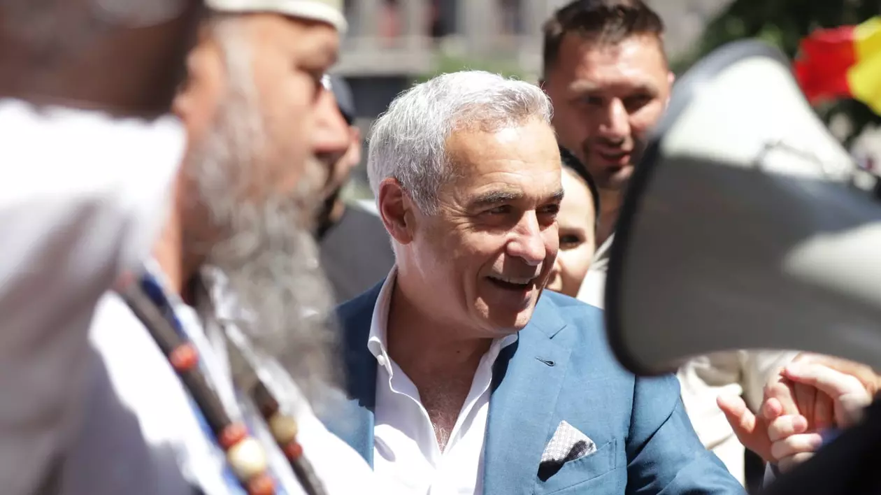 Călin Georgescu, in sacou albastru si camasa alba, zambeste larg, inconjurat de sustinatori si jurnalisti
