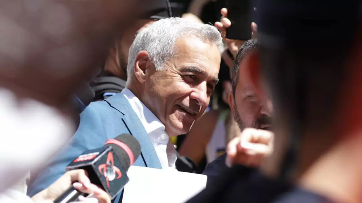 Călin Georgescu în timp ce coboră din mașină în fața Judecătoriei Sectorului 1 din București, âmbește în fața camerei și este înconjurat de manifestanți și susținători