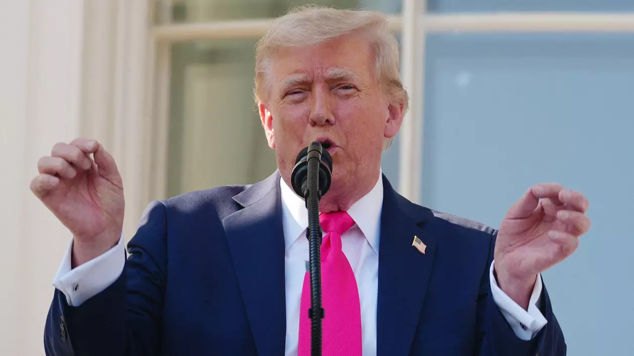 Donald Trump surprins în timp ce vorbește la microfon, la Casa Albă, în iulie 2025. Poartă un sacou negru, o cămașă albă și o cravată roz. Liderul de la Casa Albă are mâinile ridicate