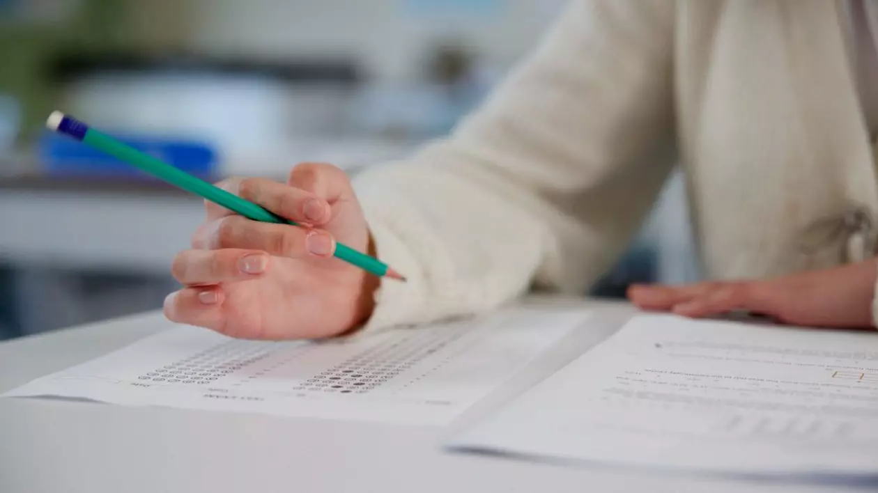 Elev care scrie cu creionul pe o foaie de hârtie la examen