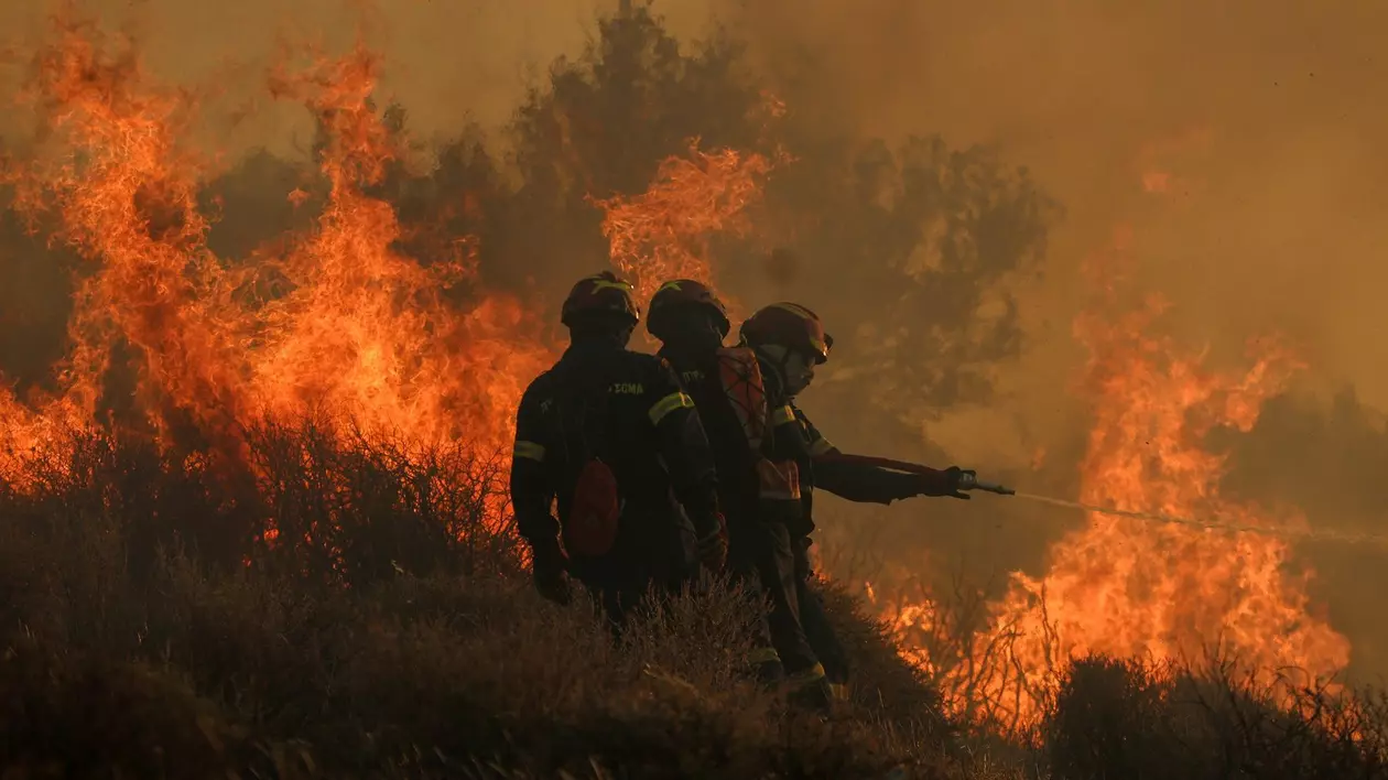 Imagine cu trei pompieri care se luptă cu flăcările din Creta, Grecia. Imaginea a fost surprinsă în iulie 2025