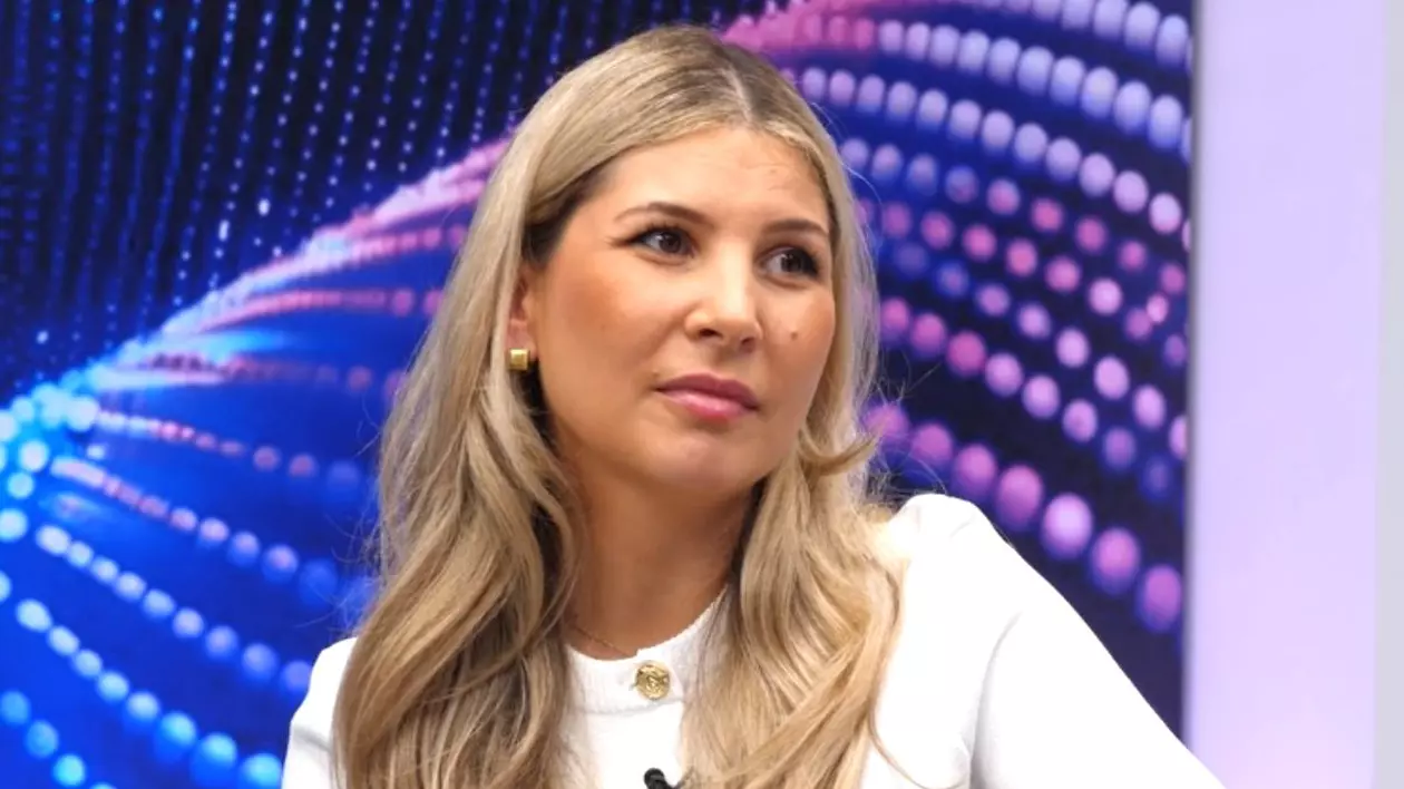 Oana Vlădilă, îmbrăcată cu o bluză albă, în platoul emisiunii Puterea unui Lider de la Libertatea, cu fundal albastru