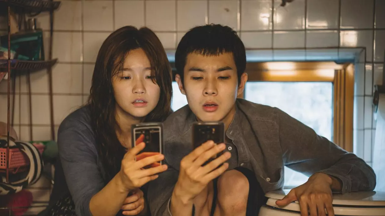 Imagine din filmul Parasite, regizat de Bong-Joon Ho, ]n care doi tineri stau pe telefoane.