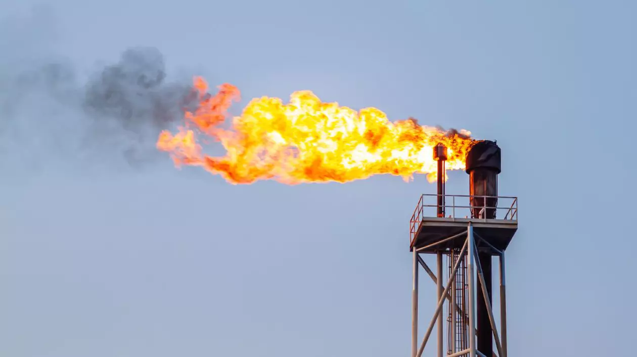 Sonda unei instalații de exploatare a gazelor naturale, care arde cu flacără deschisă, cu cerul albastru pe fundal
