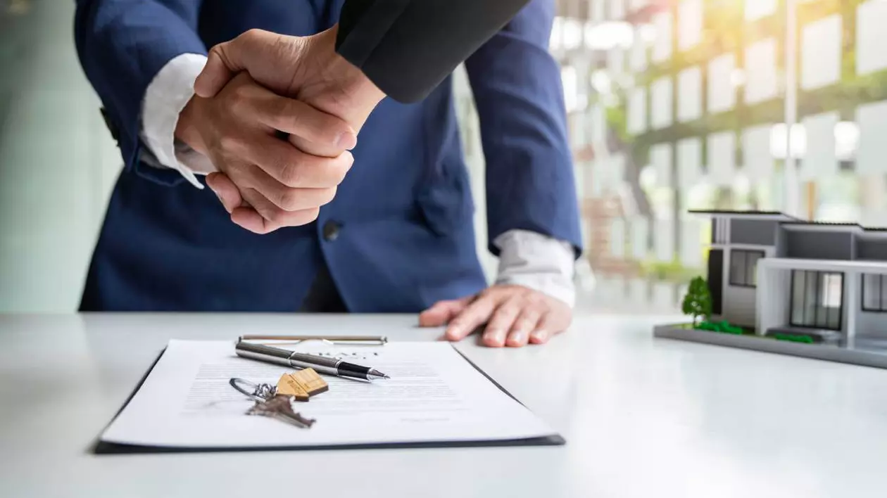 Doi bărbați în timp ce dau mân pentru că au semnat un contract de vânzare - cumpărare pentru o proprietate imobiliară
