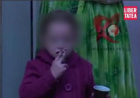 Video şocant! O fetiţă de şase ani fumează, iar mama ei îi aprinde ţigara