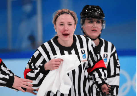 Arbitră plină de sânge, după ce a fost lovită accidental cu crosa, în timpul meciului de hochei Canada - SUA, din turneul olimpic feminin