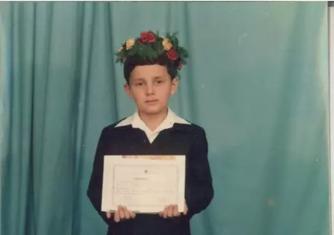 Stă sfios, cu diploma în mână și coronița pe cap! Îl recunoști? Azi e cel mai ghiduș prezentator! FOTO