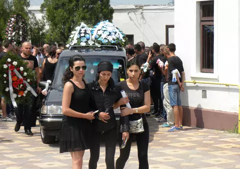 DEVASTATĂ DE DURERE! Soţia sportivului ucis la Slatina, ŢINUTĂ PE BRAŢE la înmormântare