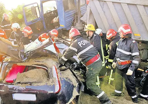 Striviți sub tone de nisip | Patru angajați ai unei firme din Craiova au ajuns cu autoturismul sub un camion