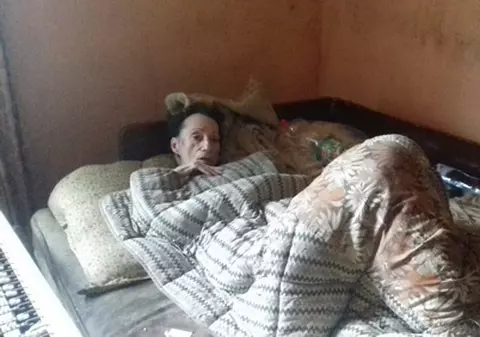 Nu poate merge din cauza bolii care i-a distrus mușchii. Drama unei femei din Brașov care trăiește din mila vecinilor