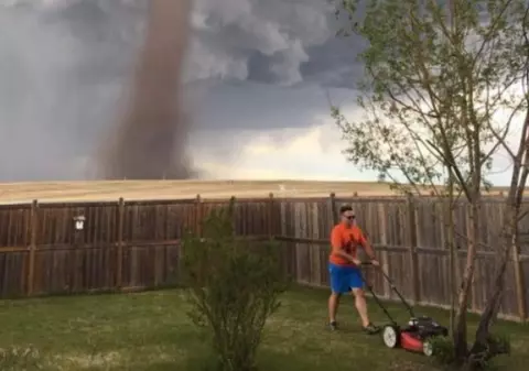 Fotografia care a devenit virală: Un bărbat tunde liniștit gazonul, în timp ce în spatele său e o tornadă