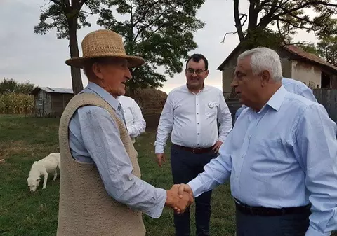 Petre Daea mănâncă jambon din portbagajul unei maşini. Ministrul laudă „savoarea şi gustul cărnii” de porc din rasa Bazna