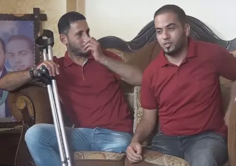 Doi tineri din Gaza împart perechea de pantofi. Fiecare are câte un picior