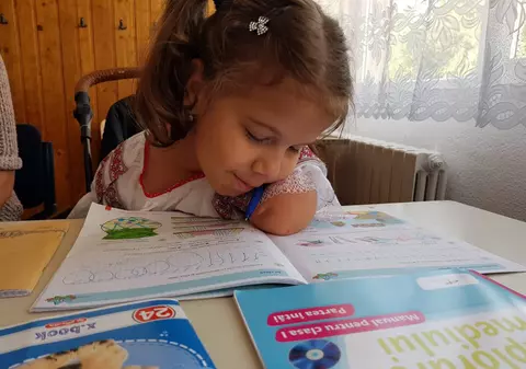 Lecția de voință a unui copil. Delia învață să scrie ajutându-se de umăr și de obraz