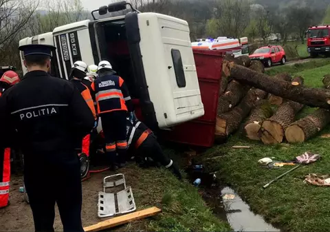 Buştenii dintr-o remorcă s-au răsturnat peste un autoturism parcat, pe un drum din Harghita. O femeie a murit si doi copii au fost răniți