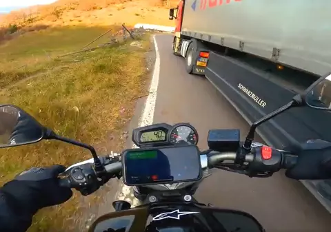 Motociclist aruncat pe câmp de un camionagiu, pe o șosea din România. Amândoi erau peste linia continuă, în curbă | VIDEO