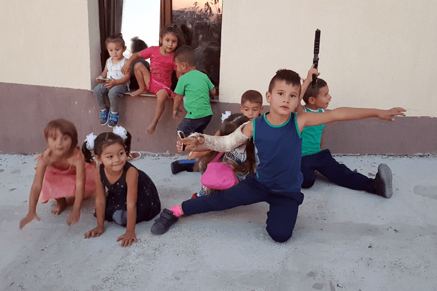 Cei mai mici dintre cei 23 de copii care locuiesc în casa construită de Părintele Damaschin se joacă în jurul clădirii, în spatele gardurilor, în timp ce copiii mai mari merg singuri pe ulițele neasfaltate din Cicoarei