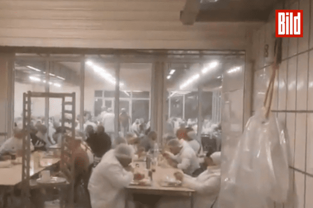 Muncitori servind masa în cantina abatorului Tönnies din Germania. FOTO: captură Bild