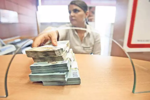 ANPC a amendat 15 bănci din România pentru publicitate înșelătoare și probleme la contracte. Care sunt acestea și ce au descoperit inspectorii ANPC. Ghișeu bancar cu mai multe teancuri de bani