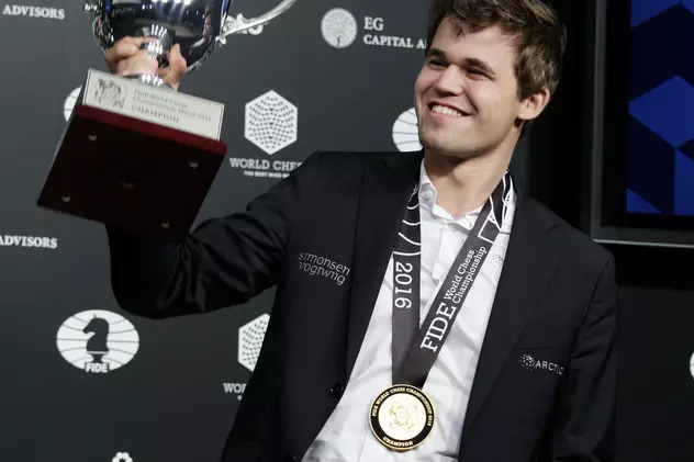 Magnus Carlsen ridică, zâmbitor, trofeul rezervat campionului mondial la șah. (FOTO: EPA)