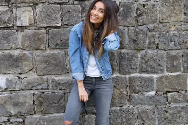 Lili Sandu, îmbrăcată în haine din jeans, pozează lângă un zid