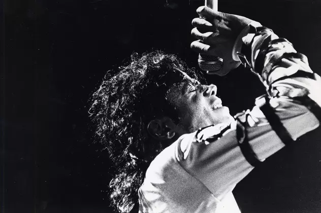 Michael Jackson, devansat în topul celor mai bine vândute albume. Fotografie alb-negru, cu Michael Jackson în timpul unui concert, cu microfonul ținut deasupra capului