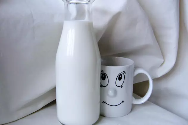 Consumul de lapte integral previne atacul vascular cerebral. Sticlă cu lapte, lângă o cană pe care e desenată o față care râde