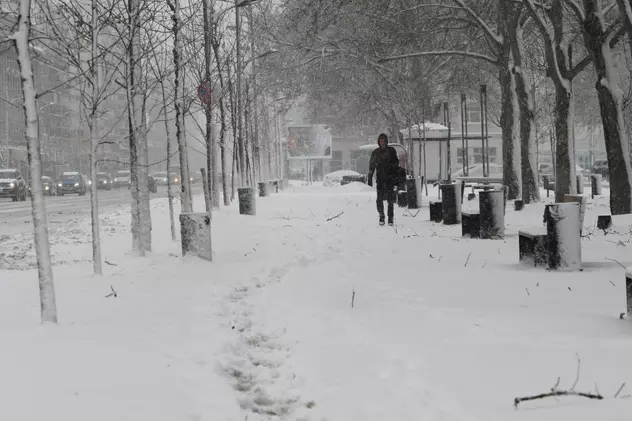 Prognoza meteo pentru 18 decembrie. Zăpadă pe trotuar, cu un om în depărtare