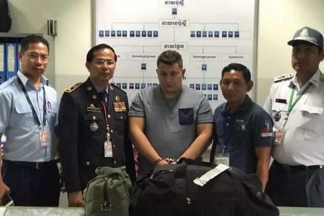 Un român a fost prins cu cinci kilograme de droguri pe un aeroport din Cambodgia. A mai avut un complice român. Ce pedeapsă riscă. Olaru (centru), între polițiștii care l-au reținut