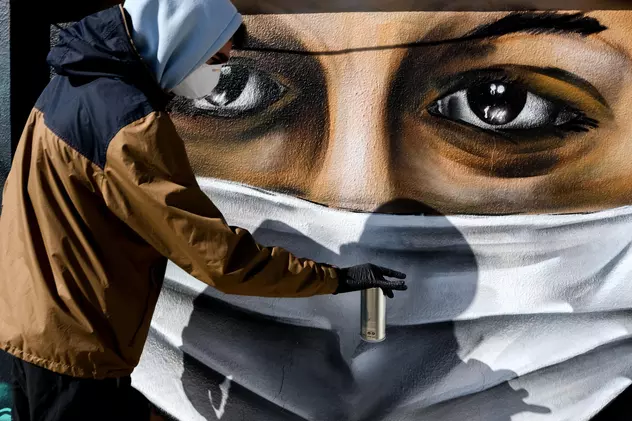 Atena, Grecia. Un artist pictează un chip de femeie acoperit cu mască