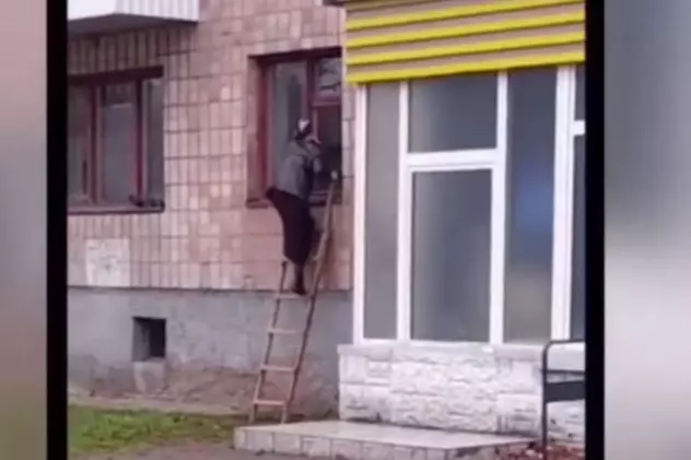 O bunicuță din Ucraina iese din bloc pe geam, cu scara, după ce la intrare a fost instalat un interfon