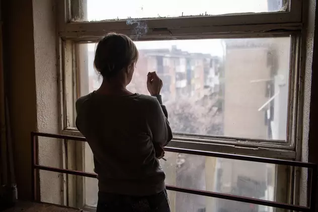 O femeie privește pe fereastră într-un bloc din Harkov, oraș bombardat de ruși încă din prima zi de război, 24 februarie. Foto: Profimedia