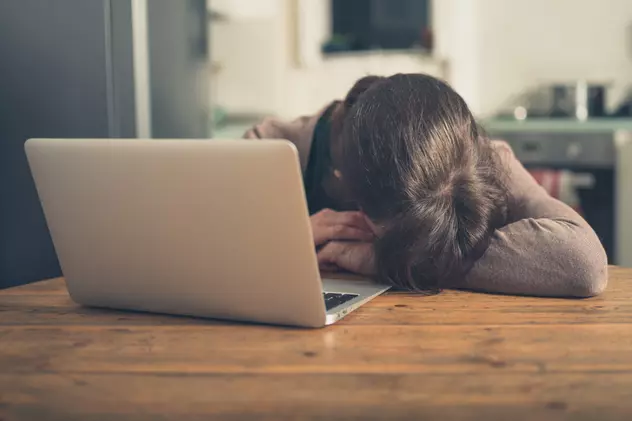 Oboseala cauze- O femeie doarme cu capul pe masa in fata laptopului