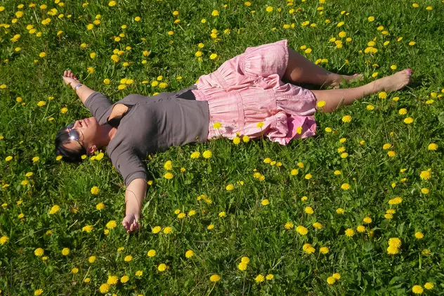 Tehnici impamantare - O femeie desculta sta intinsa pe iarba