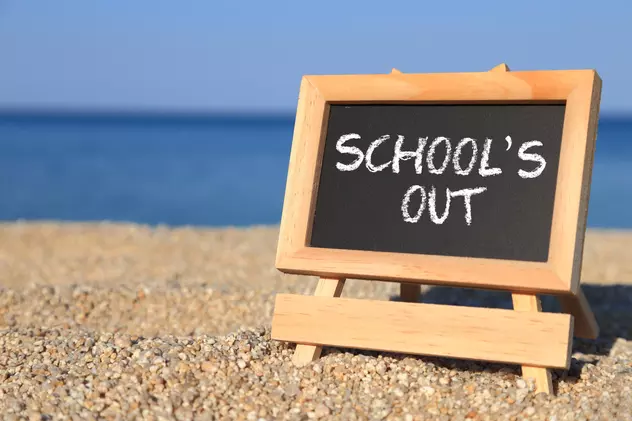 vacanta de vara 2022 - tablă cu "şcoala s-a terminat" pe o plajă