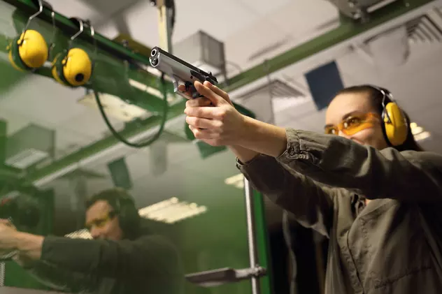 Unde poți trage cu arma în București - O tânără şi un bărbat trag cu pistolul într-un poligon de tir sportiv.