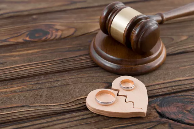 Modalităţi pentru a evita divorţul - O inimă de lemn frântă, cu câte o verighetă pe fiecare jumătate, alături de un ciocănel de judecător, toate pe o masă de lemn