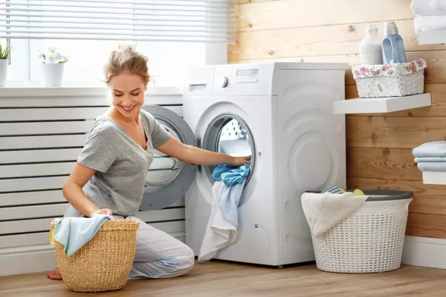 Cele mai bune maşini de spălat rufe în 2022 - O tânără scoate rufele dintr-o maşină de spălat