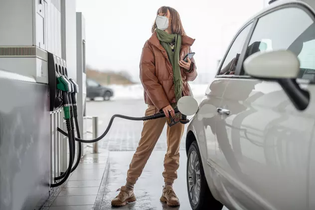 De ce nu ai voie să vorbești la telefon în benzinărie - O femeie alimentează maşina într-o benzinărie şi ţine în mână un telefon mobil.