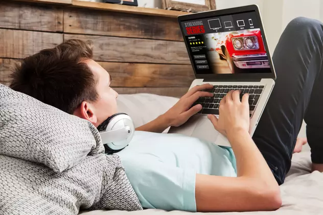 Lenovo Days îți aduce super reduceri în oferta PC Garage de azi, 30 septembrie - Imagine cu un tânăr, întins, pe un pat, care urmăreşte filme pe un laptop