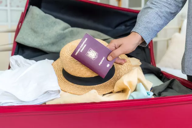 Ce trebuie să faci în cazul în care pierzi paşaportul sau îți este furat - Imagine cu o valiză şi o mână care ţine un paşaport deasupra valizei