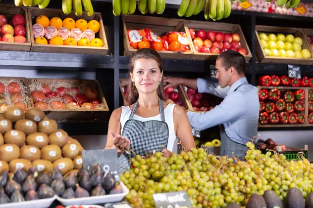 Fructele care sunt produse în cele mai mari cantităţi în lume - Imagine cu un raion de fructe dintr-un magazin, în care lucrează o femeie şi un bărbat