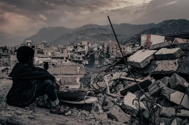 Ce sunt crimele de război și cum pot fi pedepsite - Imagine cu un copil care priveşte ruinele oraşului Taiz, distrus în războiul civil din Yemen