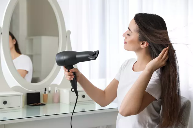 Ce uscător de păr ţi se potriveşte - Imagine cu o tânără care îşi usucă părul în faţa oglinzii