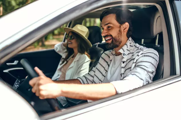 La ce să fii atent când închiriezi o maşină - Imagine cu un cuplu fericit aflat într-o maşină, în concediu
