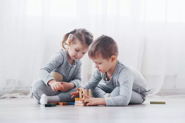 Cele mai bune jocuri pentru copii - idei de jocuri în funcție de vârstă - Imagine cu doi copii, băiat şi fată, care se joacă în casă