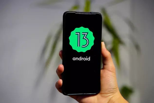 Ce aduce nou sistemul Android 13 - Imagine cu un telefon care afişează pe ecran logo-ul sistemului de operare Android 13