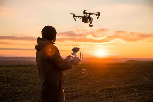 Noi reglementări privind folosirea dronelor, valabile din 2023 - Un bărbat care operează o dronă pentru a filma un apus de soare